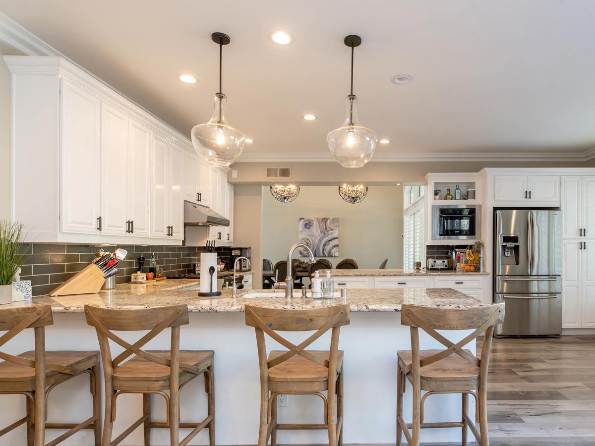 kitchen with four bar seating stools and two long, hanging lights