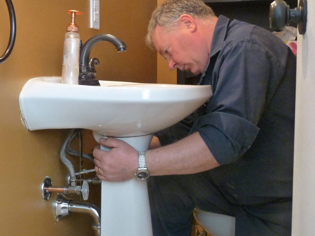 plumber working on bathroom sink installation